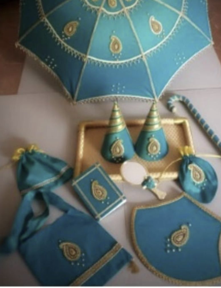 Kasi yatra set in teal and gold: umbrella, walking stick, visiri, book, and bags.